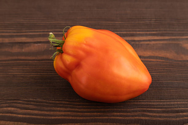 istock Red heart shape tomato on brown wooden, Side view, close up 2244924378