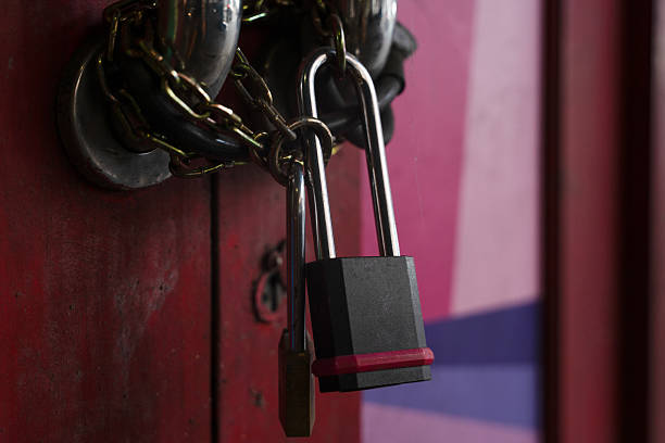 istock Rusty chain lock securing a red metal door in a dimly lit alley 2244925741