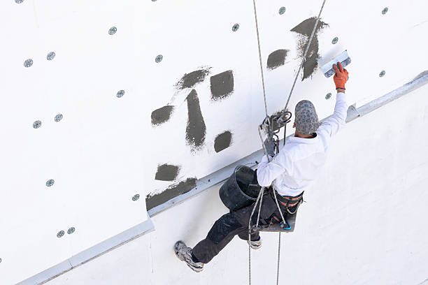 istock Construction worker seals the joints between polystyrene panels with adhesive at the height of the ninth floor of the building. 2244926705