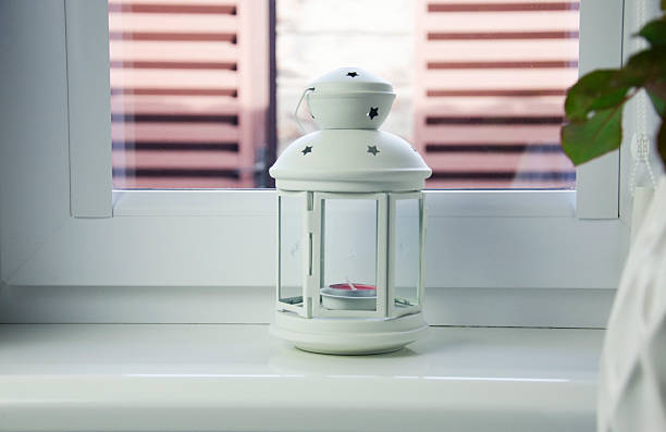 White lantern with candle on window sill — cozy home decor
