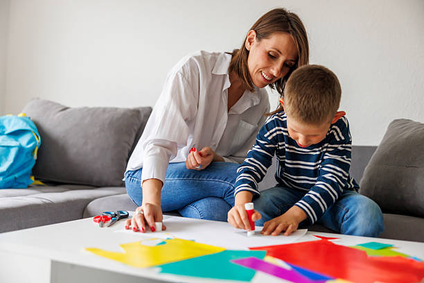 istock Mother and son cutting and gluing collage paper while doing an art project at home for homework 2244929777