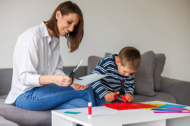 istock Mother and son cutting and gluing collage paper while doing an art project at home for homework 2244929852