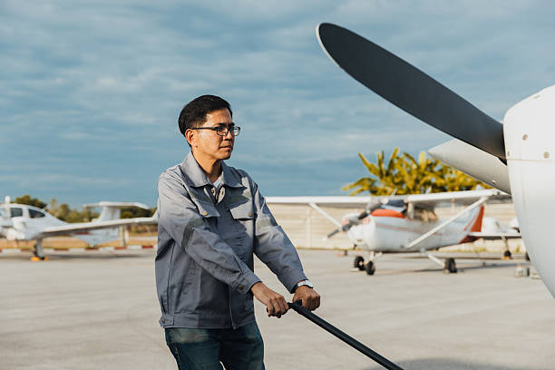 istock Man preparing small aircraft for flight on a sunny day at an airfield with several planes nearby 2244931643