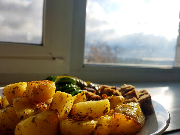 Delicious roasted potatoes and vegetables near a window.