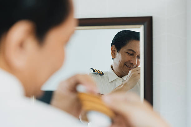 A pilot is getting ready for a day of flying, adjusting their uniform collar with a smile. This moment takes place in a well-lit room, capturing a sense of duty and pride.
