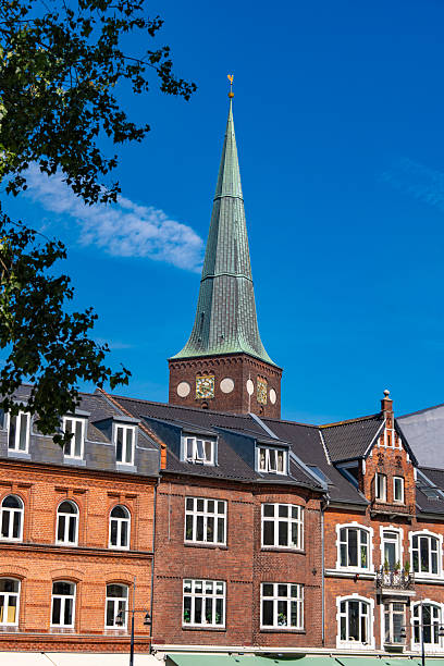 View of Aarhus Cathedral tower San Clemente rising above historic brick buildings along Aboulevarden street