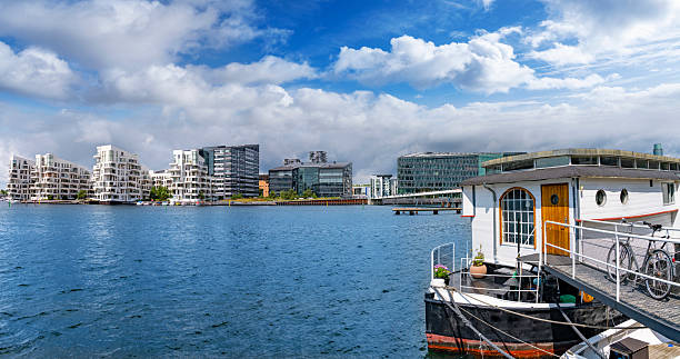 Houseboat with bicycle in Copenhagen Denmark harbor with modern residential and office waterfront skyline