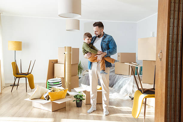 istock Father and his child in a bright new home, unpacking boxes after moving 2244939744