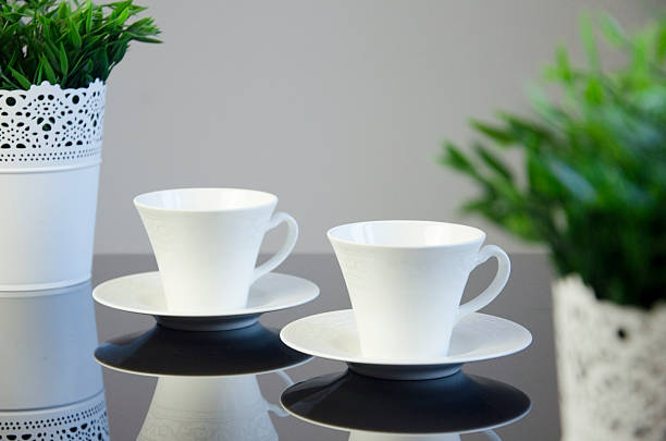 istock Elegant coffee cups with floral and minimalist designs on reflective surface 2244943142