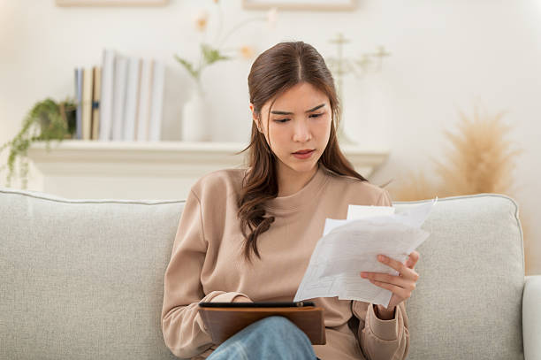 istock Asian woman feeling unhappy after looking at the bill feels stressed having financial problem, check finances, experiencing lack of money pay for loan, huge taxes, utility rates, get eviction notice 2244943214
