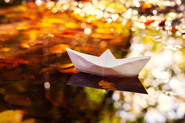 istock Paper Boat in a Puddle with Golden Autumn Light 2244949936