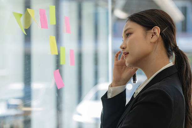 istock Confident businesswoman planning while looking at adhesive notes stuck on a glass wall. 2244958218