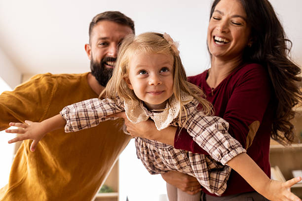 istock Parents playing airplane game with daughter at home 2244960219