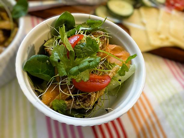 Healthy and colorful salmon salad bowl served with fresh greens, avocado, cherry tomatoes, cucumber, and a light dressing. Captured from above in natural light to highlight the freshness and vibrant textures of the ingredients — a modern, nutritious meal concept.