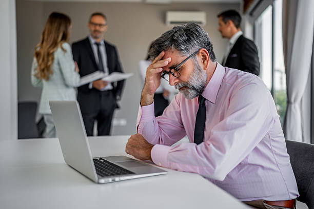 istock Stressed businessman having headache working on laptop in office 2244965253