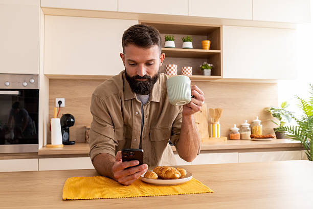 istock Young man reading news on smartphone at breakfast 2244966556