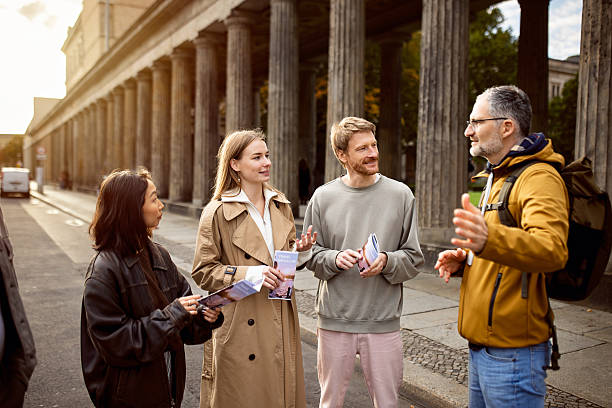 istock Tour Guide Explaining Berlin History to Diverse Young Tourists Holding Sightseeing Brochures in Front of Kolonnadenhof 2244968492