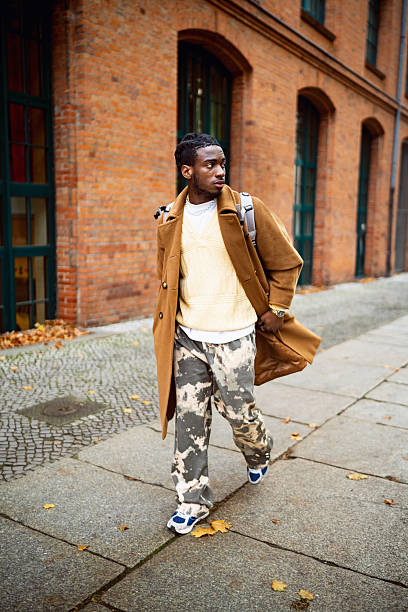istock Young Stylish Black Man Passing By a Brick Wall in Berlin 2244971874