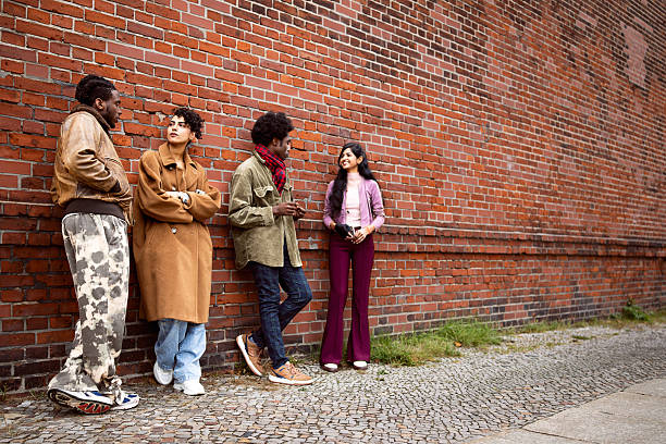 istock Young Diverse Tourists Taking a Break and Talking While Leaning on a Brick Wall in Berlin 2244972029