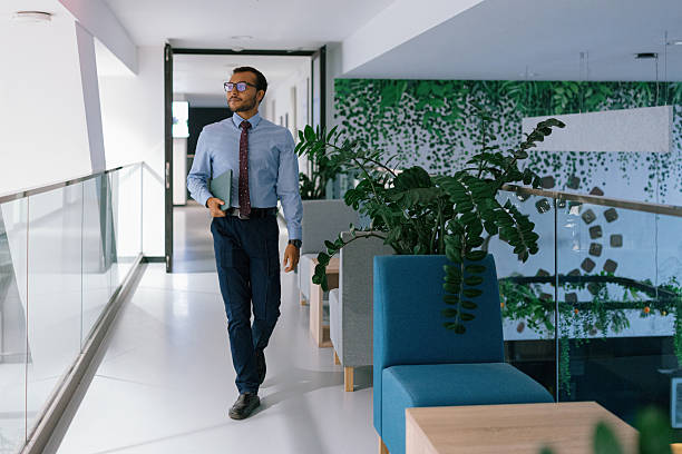 istock Confident businessman walking through office hallway holding tablet 2244973709