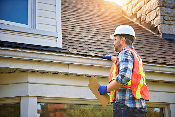 man with hard hat standing on steps inspecting house roof