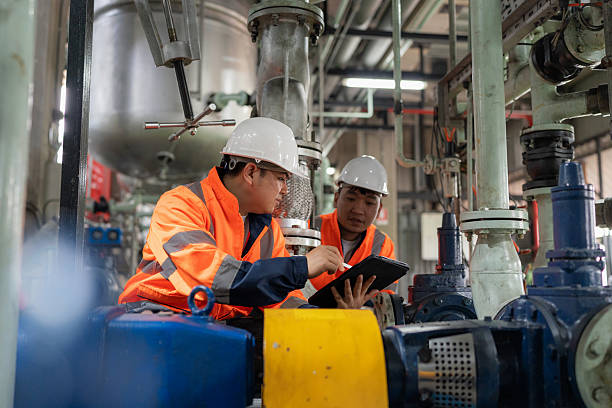 istock Engineers wearing safety helmets inspect pipeline systems linked to lubricant tanks at a petrochemical plant. Teamwork, safety, and technology drive their discussion on boosting production efficiency in the oil and energy industry. 2244976317