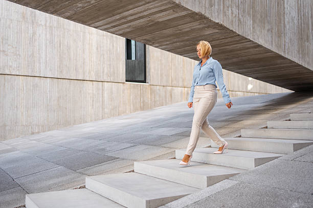 istock Confident businesswoman walking down steps near modern building 2244979097