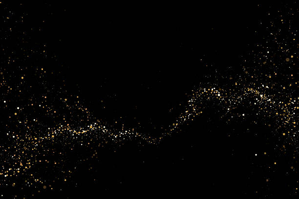 Gold glitter dust particles sparkling on black background