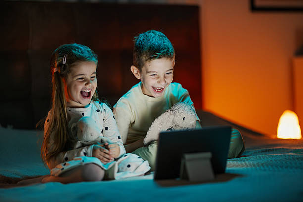 istock Happy siblings laughing watching movie on digital tablet 2244982900