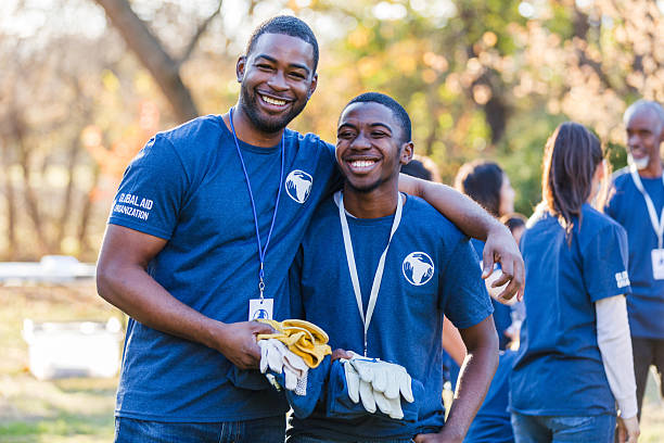 istock Volunteers with arms around each other, smiling happily while working outdoors together. 2244985467