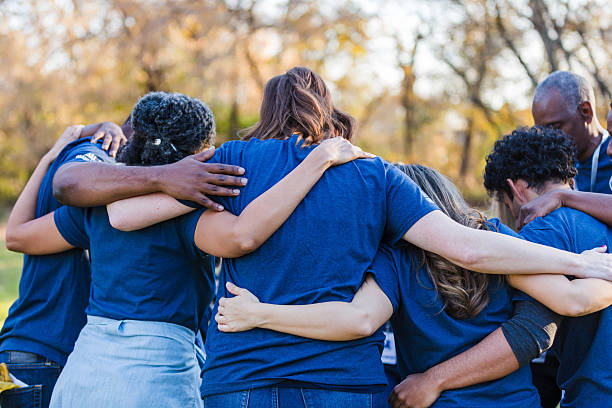 istock Diverse group of people embracing in a circle, showing unity and shared purpose outdoors. 2244985469