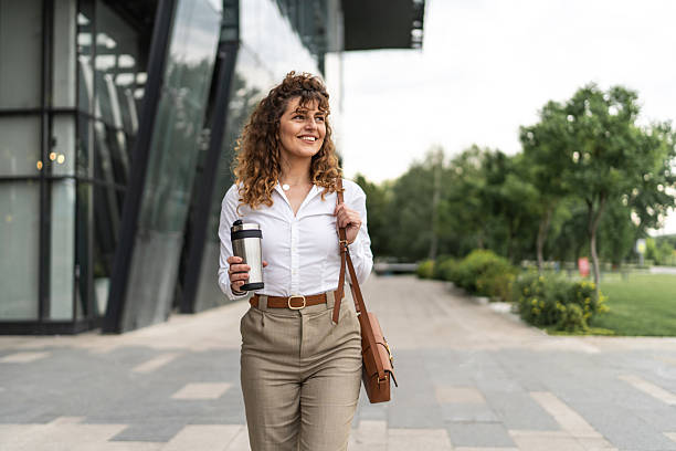 istock Professional woman commuting to work with coffee outside office building 2244986183