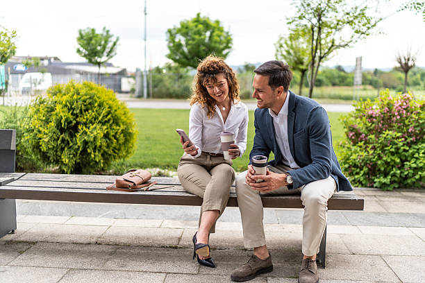 istock Business colleagues relaxing on bench, sharing content on smartphone 2244987256