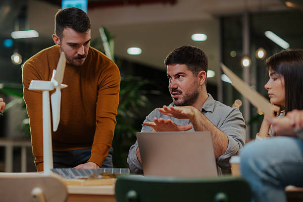 istock Team discussing renewable energy project with wind turbine model 2244988668