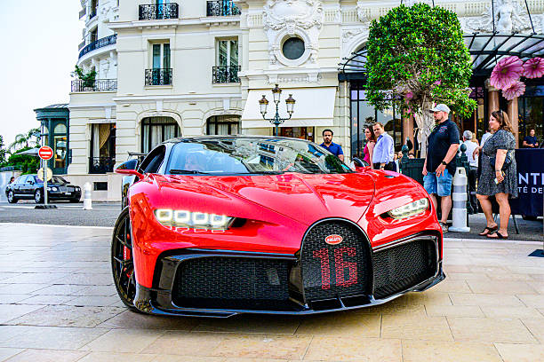 Bugatti Chiron hypercar driving on the street in front of the Hotel de Paris in Monte Carlo, Monaco, during a summer evening. The Bugatti Chiron is a hypercar renowned for its extraordinary performance, luxury, and engineering precision. Powered by an 8.0-liter quad-turbocharged W16 engine producing 1,479 horsepower, it accelerates from 0–60 mph in under 2.5 seconds and reaches an electronically limited top speed of 261 mph (with special variants exceeding that). Its seven-speed dual-clutch transmission delivers seamless power to all four wheels, while an adaptive suspension ensures stability at extreme speeds.