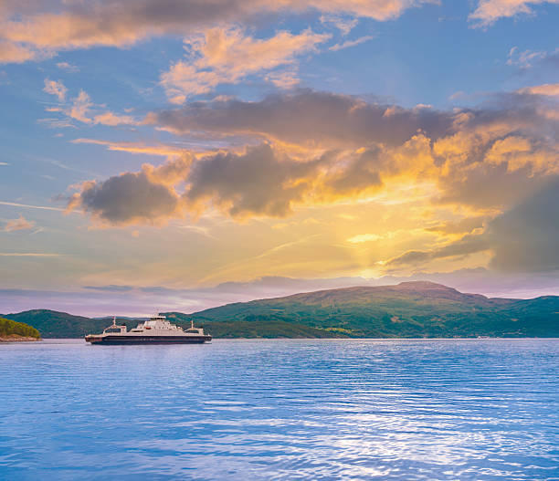 Hardangerfjord ferry on calm blue water at summer sunset with green mountains and dramatic clouds