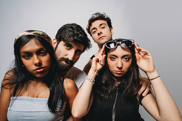 Four young diverse adults posing against a plain background, creating a modern group portrait showing friendship and youth