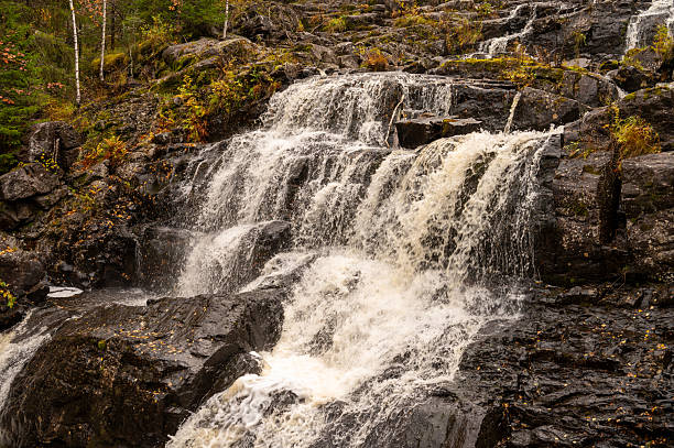 istock Cascading waterfall over rocky terrain in autumn forest scenery 2244993885
