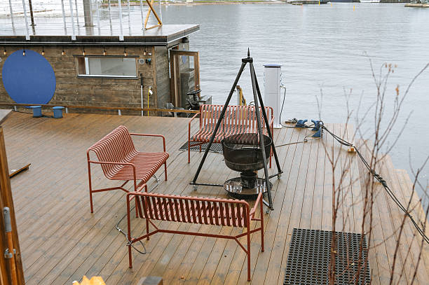 Cozy lakeside patio with red benches and fire pit on wooden deck.