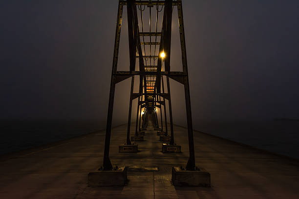 Pre dawn on a foggy night on the Grand Haven south pierhead with the inner light beacon and outer lighthouse.