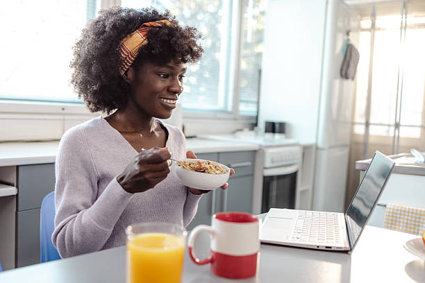 istock Woman enjoys a healthy breakfast while working from home at a sunlit kitchen 2244997843