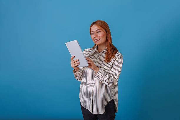 istock Woman smiling while using digital tablet, engaging with technology for business or personal browsing 2244998339