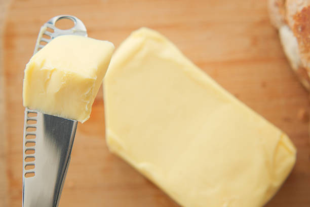 Butter board preparing, spreading butter and cottage cheese topping over wood serving board, closeup