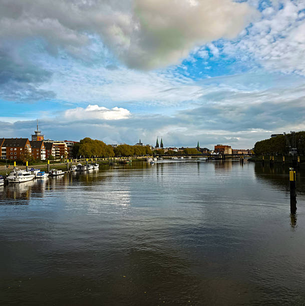 River with ships, surrounded by urban buildings and trees under a cloudy sky, view from the Stephanie Bridge of the Weser in 28199 Bremen, Germany