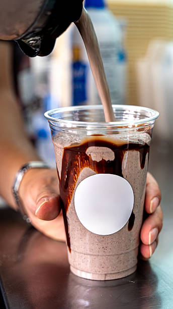 Pouring chocolate milkshake into drink cup for dessert