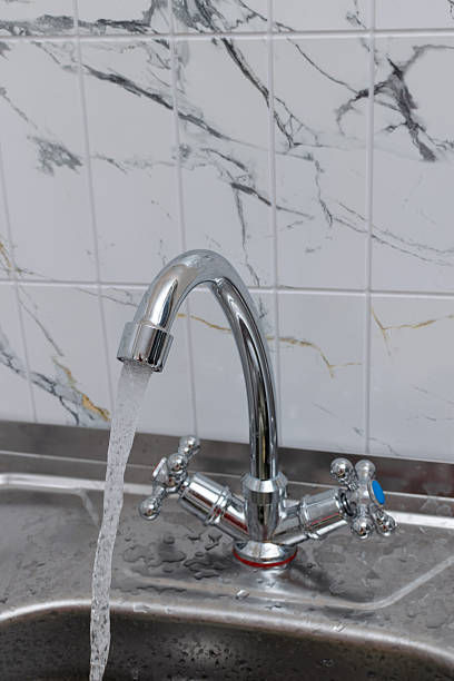 istock Modern Chrome Kitchen Faucet with Running Water and Marble Tile Background 2245005063