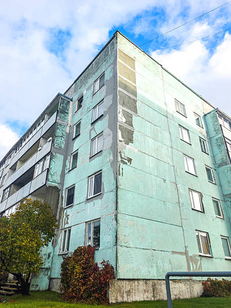 Old Soviet-era apartment building in Latvia with worn facade, peeling paint, and visible cracks, symbolizing aging architecture and urban decay