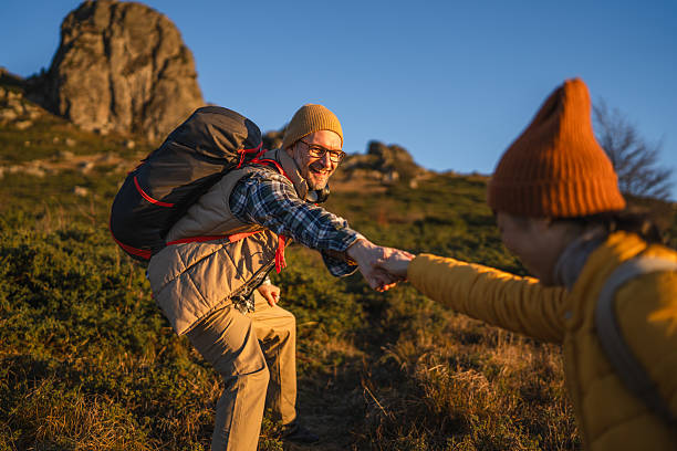 istock Couple hiking mountains receiving helping hand from partner 2245006726