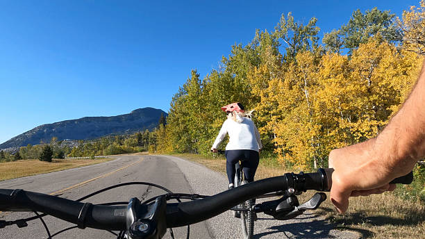 Personal perspective of couple riding e-bikes on mountain road, Bellevue, Crowsnest Pass, Alberta