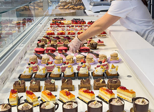 istock Low section of woman laying out pastries in display case 2245018669
